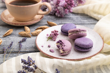 Fototapeta na wymiar Purple macarons or macaroons cakes with cup of coffee on a gray wooden background. Side view.