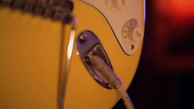 Plugging the jack into an electric guitar. Strat style butterscotch electric guitar