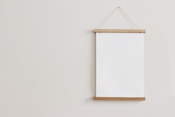 Blank wooden picture frame hanging on beige wall. Empty poster mockup for art display. Minimal...