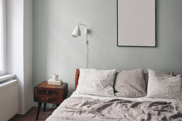 Bedroom view. Grey linen and white linen pillows on wooden bed. Scandinavian interior. Cup of...