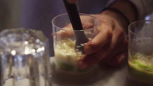 Barman preparing drink with mint, yellow sugar and lime  in a bar