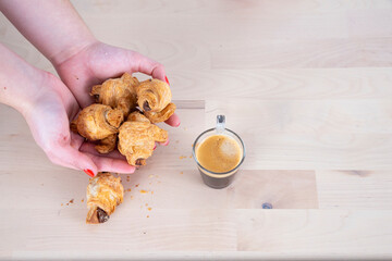 White woman hands with red nails, Glass Cup of Coffee, on wooden board background, with chocolate croissant
