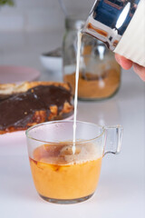 Cup of Tea falling splash of milk, on white background with chocolate puff pastry, whole grain panela. white brick wall background