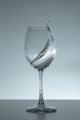 Splash of water in a glass on a gray background.