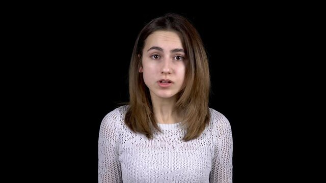 A young woman shows disgust emotions on her face. Woman contorts her face from abomination on a black background.