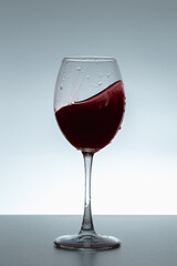 Splash of wine in a glass on a gray background.