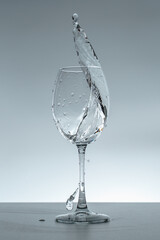 Splash of water in a glass on a gray background.