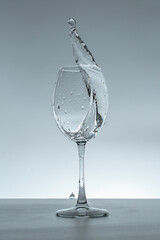 Splash of water in a glass on a gray background.
