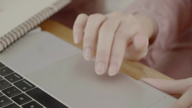 Close Up hand on a Laptop Computer. Device is Used on a Kitchen Table in a Modern Home. Person Uses Touch Pad.