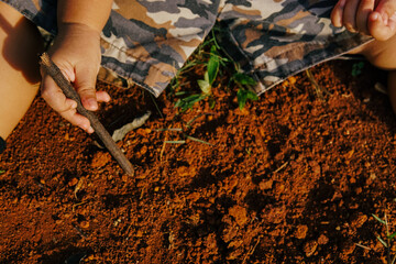 the boy's hand was playing on the dirty ground