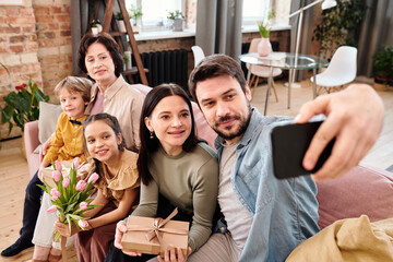 Happy family of five making selfie on large soft comfortable couch at home