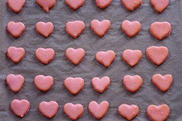 Obraz premium Pink heart homemade macaron cookies on parchment paper on a baking sheet