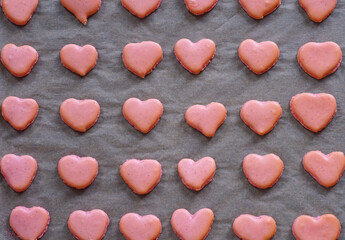 Obraz premium Pink heart homemade macaron cookies on parchment paper on a baking sheet