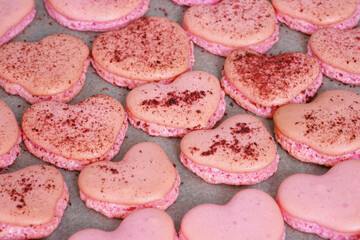 Pink heart homemade macaron cookies on parchment paper on a baking sheet