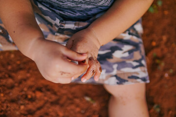 the boy's hand was playing on the dirty ground