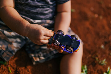 a baby's hand is playing with a toy car with a hand covered in dirt