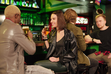 Young smiling brunette woman in casualwear having beer with her boyfriend