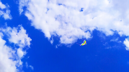 horizontal photo of the sky with a colorful airplane, in the middle of white clouds