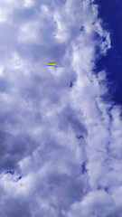 Fototapeta na wymiar the blue sky is almost completely covered with white clouds with a colored kite