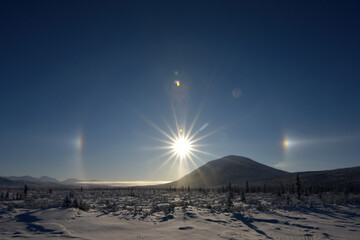 Ice crystals in the atmosphere create a halo around the sun with sun dogs to the left and right.