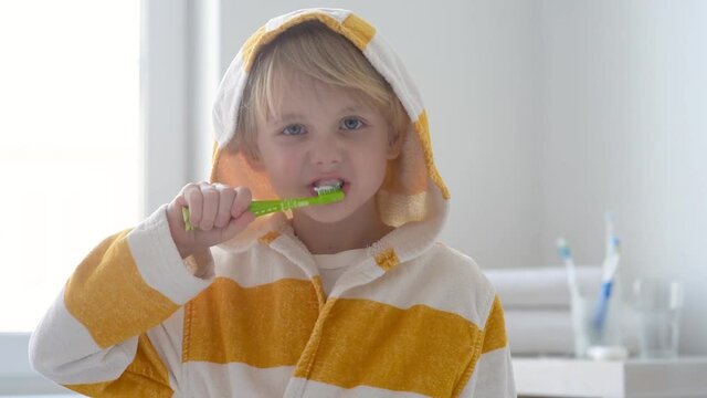 Preschooler boy cleaned teeth with dental floss and then is brushing his teeth with toothbrush carefully. Learning children proper oral hygiene. Dental medicine and healthcare for kids.