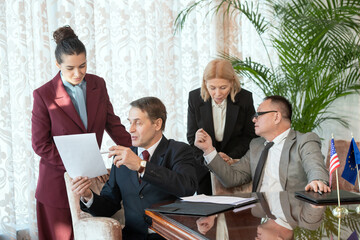 Two delegates in formalwear consulting with secretaries while reading contract