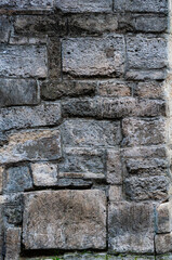 Very old wall building is made stone blocks different sizes, antique surface has been affected by time, rough texture stone