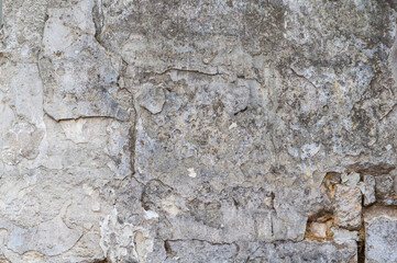 Ancient rough wall surface with shabby decorative plaster, rough textured background, weathered building material.