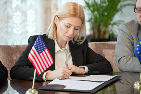 Mature American delegate in formalwear signing contract of business partnership - Powered by Adobe