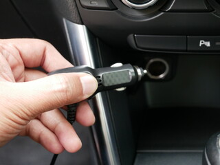 hand holding plug 12 volt into socket from car cigarette lighter.