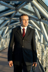 Confident mature delegate or businessman standing inside business center