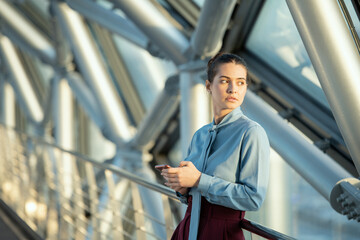 Young brunette delegate or businesswoman in formalwear using mobile phone