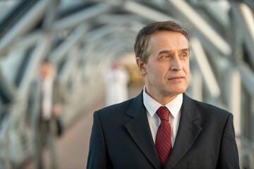 Confident mature delegate or businessman in suit standing in front of camera