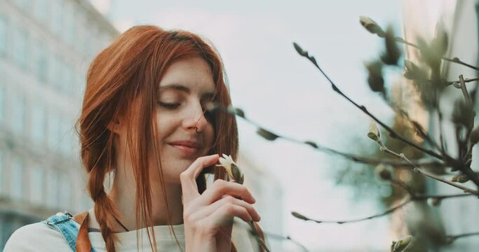 Young happy redhead woman playing with flowers
