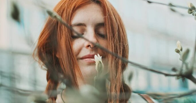 Woman smelling a flower and looking straight at the camera