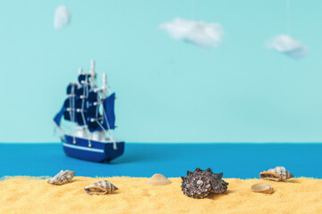 Installation of seashells on a sandy beach against the backdrop of a sailing ship sailing away.