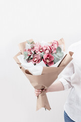 Fashionable bouquet with red orchids in hands of woman. Beautiful flowers as gift for birthday and holiday.