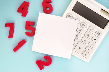 A white blank sheet lies on a white calculator near the scattered red numbers. The concept of education and teaching mathematics