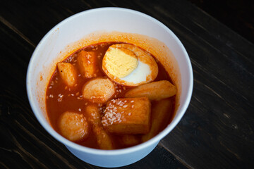 Stir-fried Rice Cake Tteok-bokki in a takeaway container. Korean food delivery.