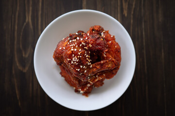 Chunks of fried chicken in a spicy sauce and sesame seeds. Food Korean cuisine on a wooden background.