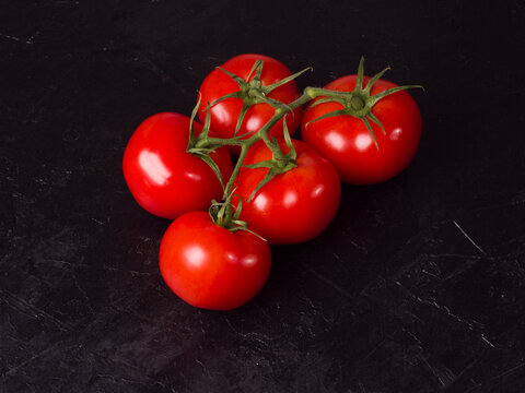 Red tomatoes on a black background. Studio photo