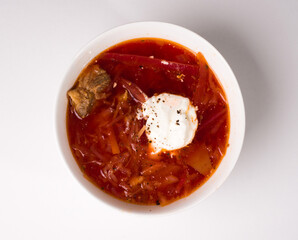 Borscht in a white round bowl. Red Ukrainian soup. Studio photo on white background