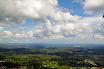 Cumulus clouds in the sky and cloud shadow on the ground as seen from the top of the hill