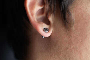 piercing in a man's ears closeup,ear tunnel