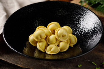 Delicious traditional Russian dumplings, handmade dough with turmeric. Still life on a wooden board. Close-up.