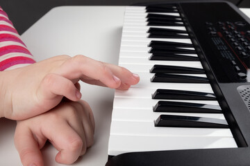 learning to play the piano,little girl hands on synthesizer keys