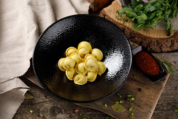 Delicious traditional Russian dumplings, handmade dough with turmeric. Still life on a wooden board. Close-up.
