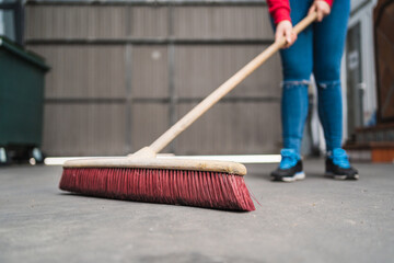 Closeup shot of a female cleaning with a long broom
