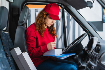Female delivery driver signing a package in the van