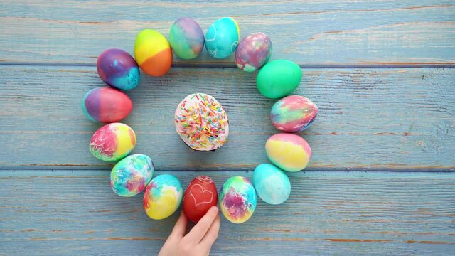 Easter cake and decorated eggs on turquoise wooden background. a child's hand puts down a red egg with a heart. a traditional holiday treat.